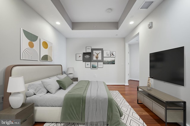 bedroom with a raised ceiling and hardwood / wood-style floors