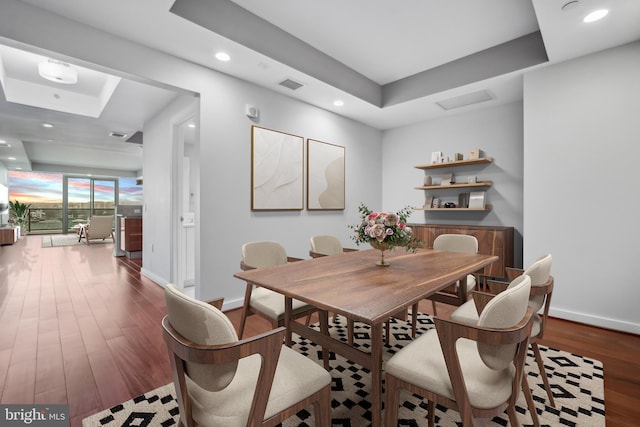 dining area featuring dark hardwood / wood-style flooring and a tray ceiling