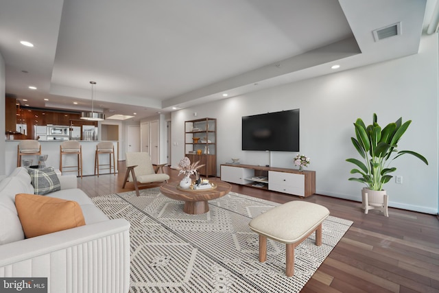 living room with dark hardwood / wood-style flooring and a raised ceiling