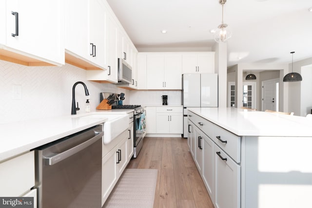 kitchen featuring white cabinetry, appliances with stainless steel finishes, tasteful backsplash, and pendant lighting