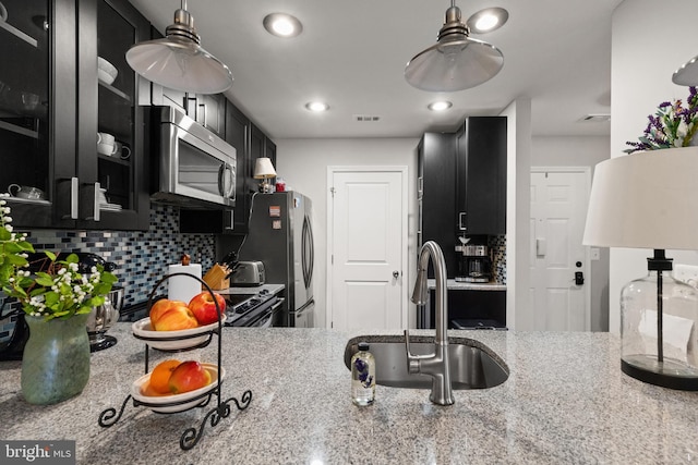 kitchen featuring tasteful backsplash, appliances with stainless steel finishes, sink, and light stone counters