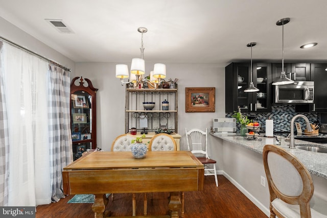 dining area with sink, a chandelier, and dark hardwood / wood-style flooring