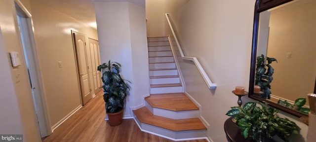 staircase featuring wood finished floors and baseboards