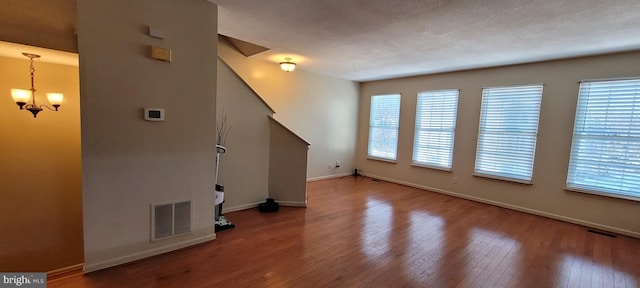 unfurnished living room with hardwood / wood-style flooring, plenty of natural light, and visible vents