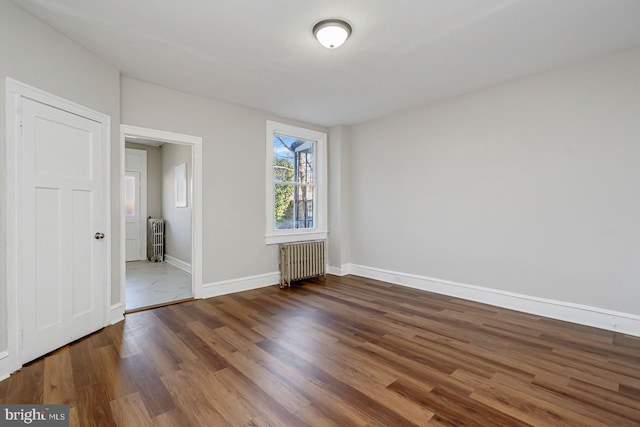 spare room featuring dark hardwood / wood-style flooring and radiator