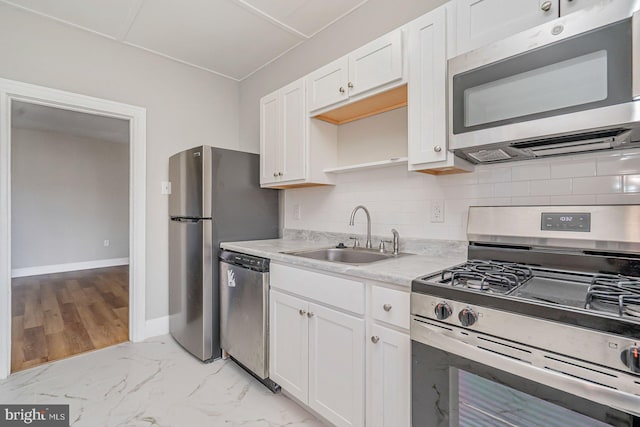 kitchen featuring white cabinetry, sink, backsplash, and appliances with stainless steel finishes