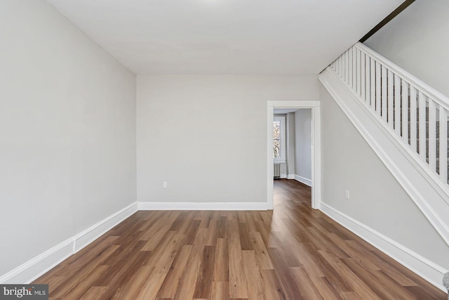 spare room featuring radiator heating unit and hardwood / wood-style floors