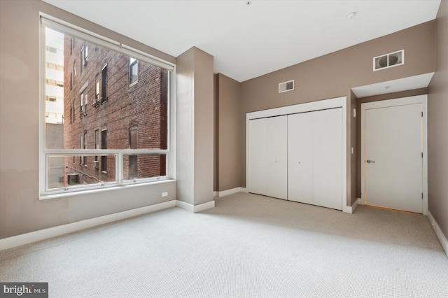 unfurnished bedroom with light colored carpet and a closet