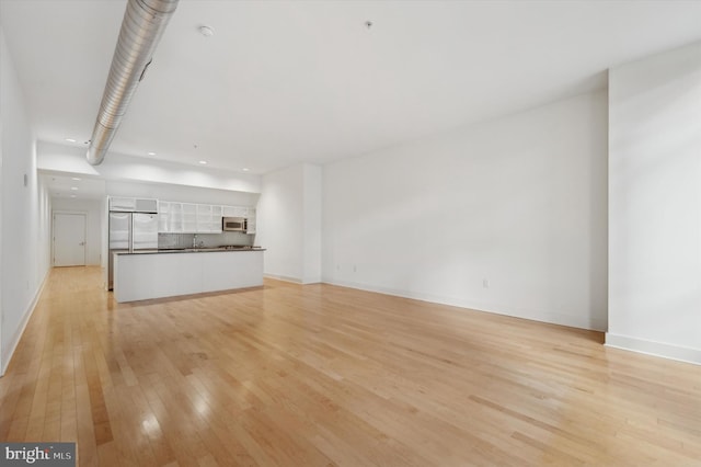 unfurnished living room with sink and light hardwood / wood-style floors