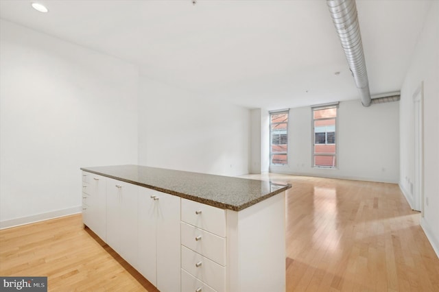 kitchen featuring light hardwood / wood-style floors, dark stone counters, and white cabinets