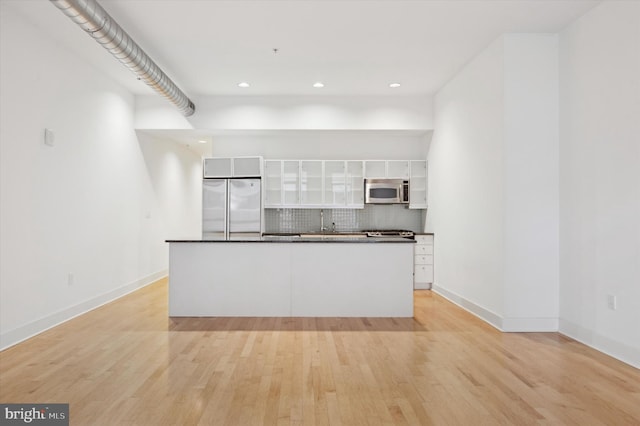 kitchen featuring stainless steel appliances, white cabinetry, tasteful backsplash, and light hardwood / wood-style flooring