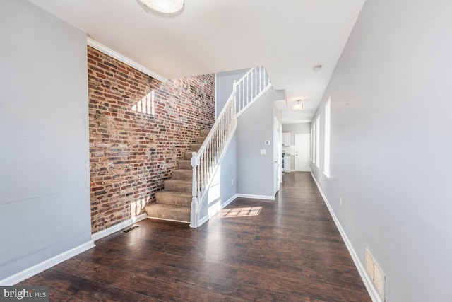 staircase with hardwood / wood-style flooring and brick wall