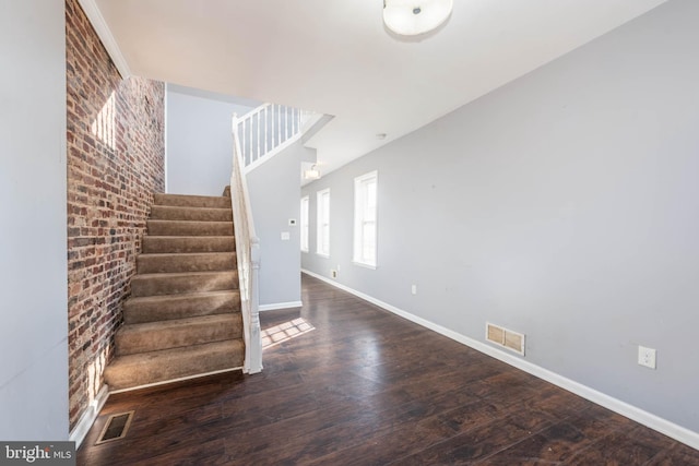 stairway featuring hardwood / wood-style flooring and brick wall