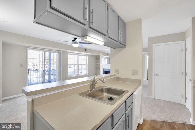 kitchen with dishwasher, sink, gray cabinetry, and kitchen peninsula