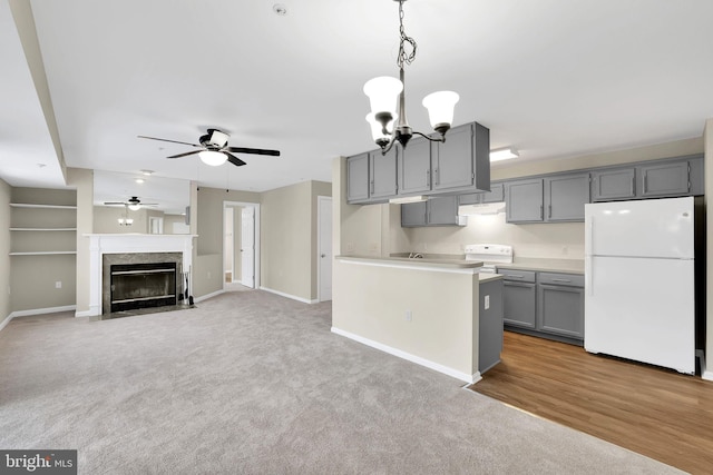 kitchen featuring gray cabinets, ceiling fan with notable chandelier, hanging light fixtures, light carpet, and white appliances