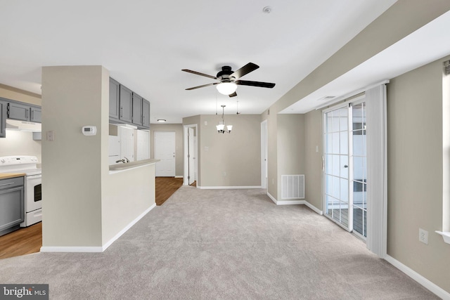 unfurnished living room featuring carpet floors and ceiling fan with notable chandelier