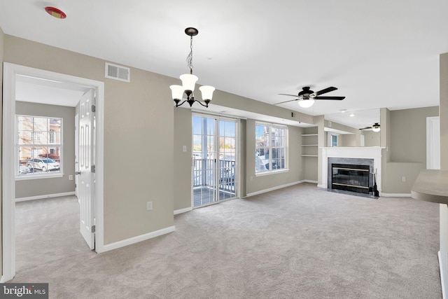 unfurnished living room featuring ceiling fan with notable chandelier and light carpet