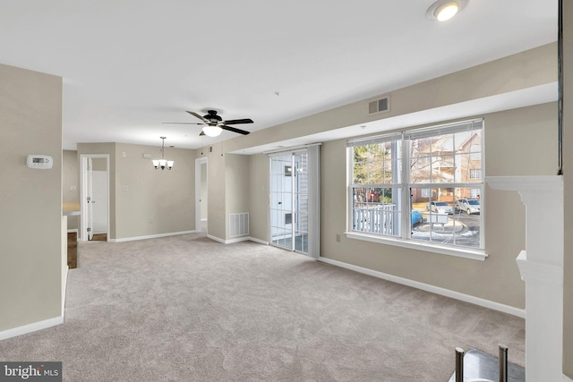 carpeted spare room with ceiling fan with notable chandelier