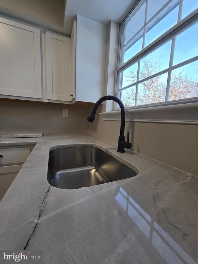 interior details featuring white cabinetry and sink