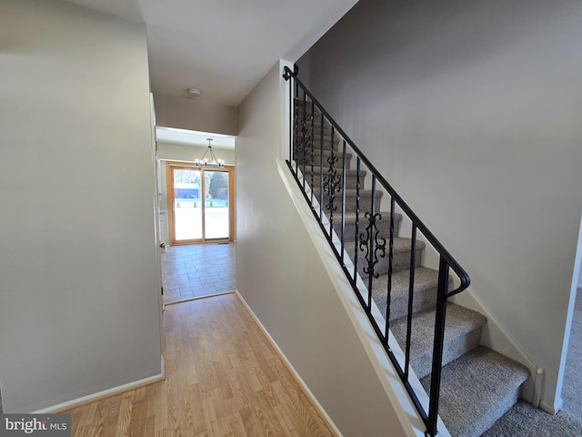 stairs featuring hardwood / wood-style floors and a notable chandelier