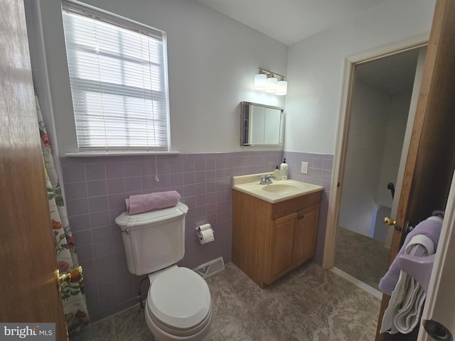 bathroom featuring tile patterned floors, vanity, toilet, and tile walls