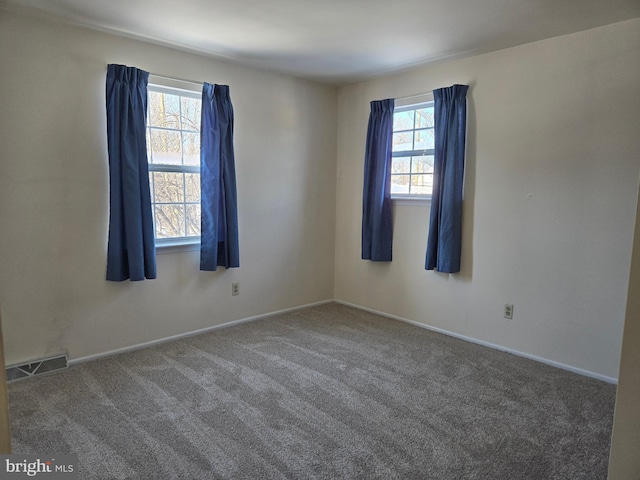 empty room featuring a healthy amount of sunlight and dark carpet