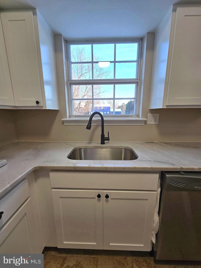 kitchen featuring stainless steel dishwasher, sink, and white cabinets