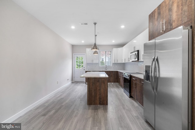 kitchen with pendant lighting, tasteful backsplash, white cabinets, a center island, and stainless steel appliances