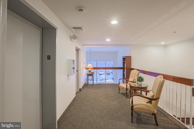 hallway with elevator and carpet flooring