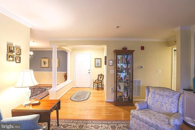 living room with hardwood / wood-style floors, crown molding, and ornate columns