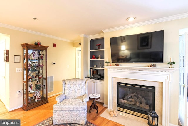 sitting room with a premium fireplace, crown molding, and light hardwood / wood-style flooring