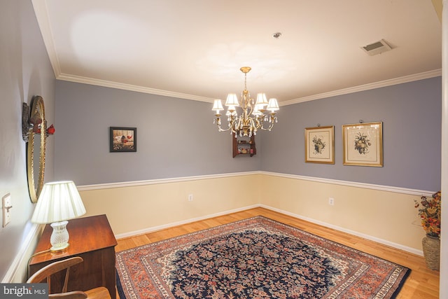 dining space with hardwood / wood-style flooring, crown molding, and a chandelier