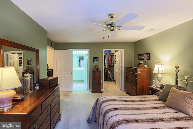 bedroom with ceiling fan, connected bathroom, light carpet, a spacious closet, and a closet