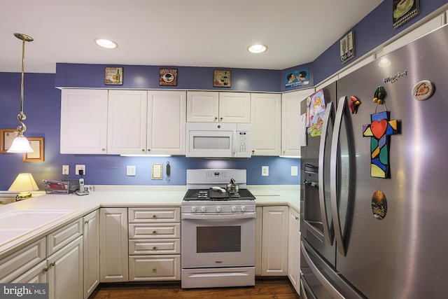 kitchen with dark hardwood / wood-style flooring, hanging light fixtures, white appliances, and white cabinets