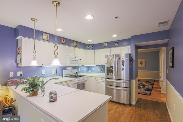 kitchen with white cabinetry, pendant lighting, white appliances, and kitchen peninsula