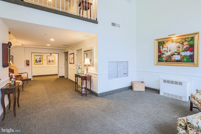 corridor with radiator heating unit, dark carpet, and mail boxes