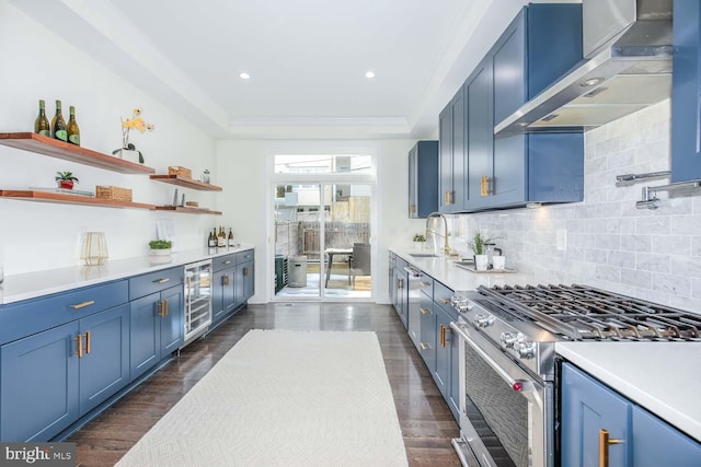 kitchen featuring wine cooler, wall chimney range hood, high end stainless steel range, and blue cabinetry