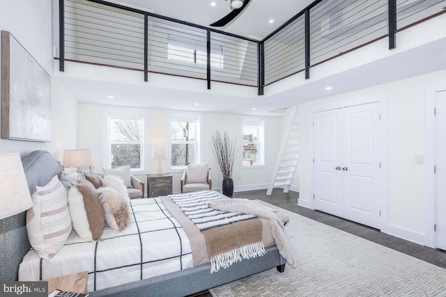 bedroom with a high ceiling, dark wood-type flooring, and a closet