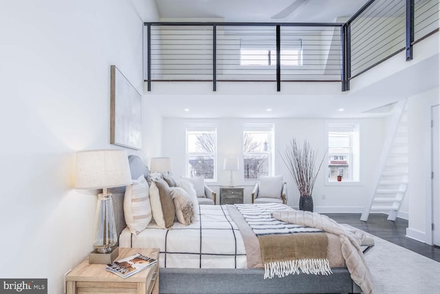 bedroom with a towering ceiling and dark hardwood / wood-style floors