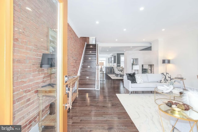 unfurnished living room with dark hardwood / wood-style flooring, ornamental molding, and brick wall