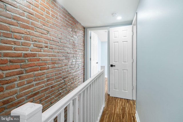 hall with hardwood / wood-style flooring and brick wall