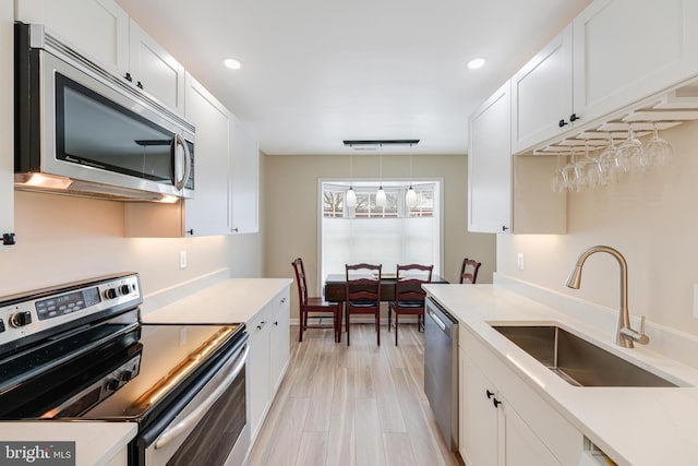 kitchen with appliances with stainless steel finishes, decorative light fixtures, sink, and white cabinets