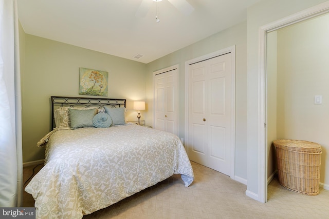 carpeted bedroom featuring multiple closets and ceiling fan