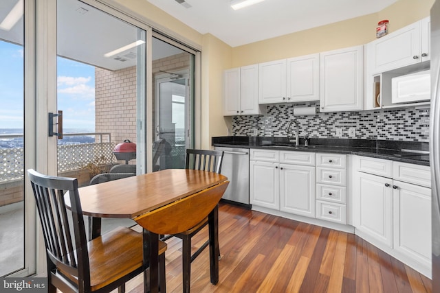 kitchen featuring dark hardwood / wood-style floors, dishwasher, sink, white cabinets, and decorative backsplash