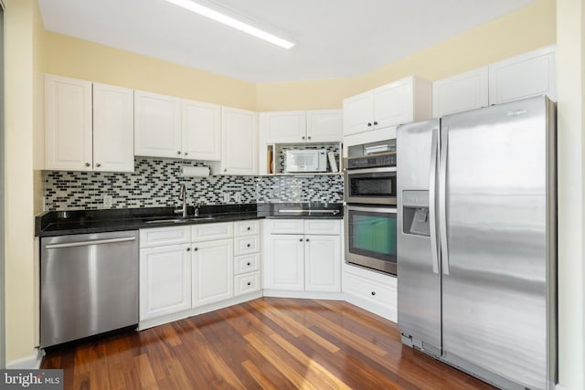 kitchen featuring sink, white cabinetry, appliances with stainless steel finishes, dark hardwood / wood-style flooring, and decorative backsplash