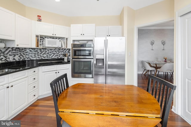 kitchen featuring stainless steel appliances, white cabinetry, and decorative backsplash