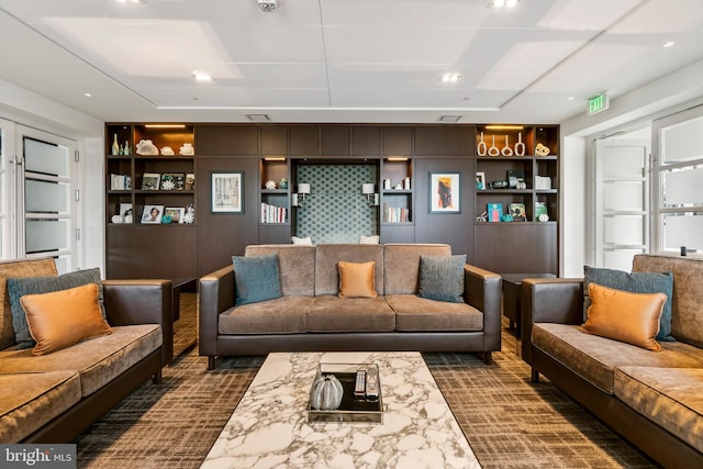 living room featuring built in shelves and dark colored carpet