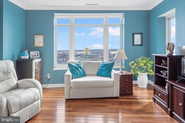 sitting room with crown molding, hardwood / wood-style flooring, and a wealth of natural light