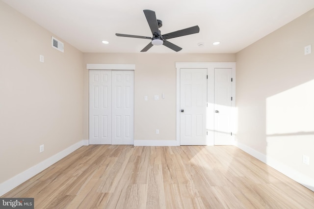 unfurnished bedroom with multiple closets, light wood-type flooring, and ceiling fan