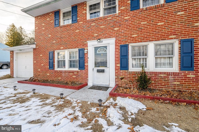 snow covered property entrance with a garage